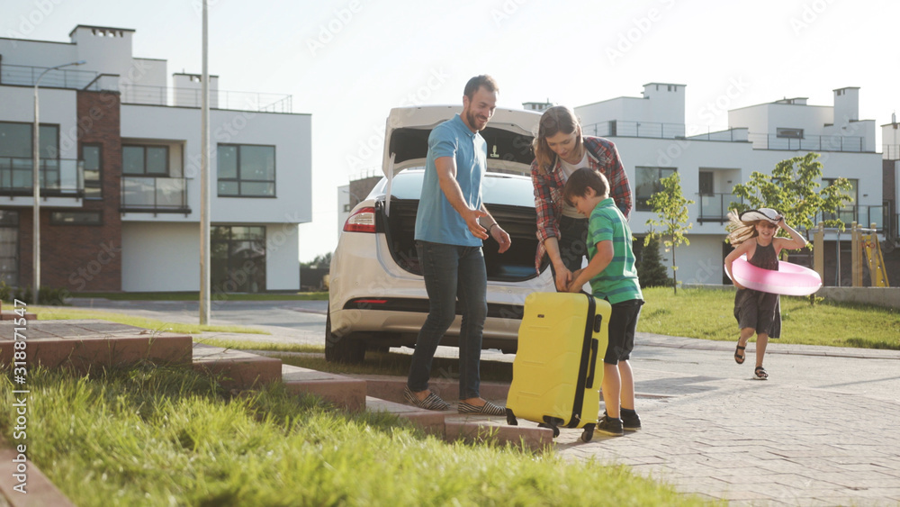 Nice Family Moments. Busy Happy Parents Loading Luggage Into A Car 