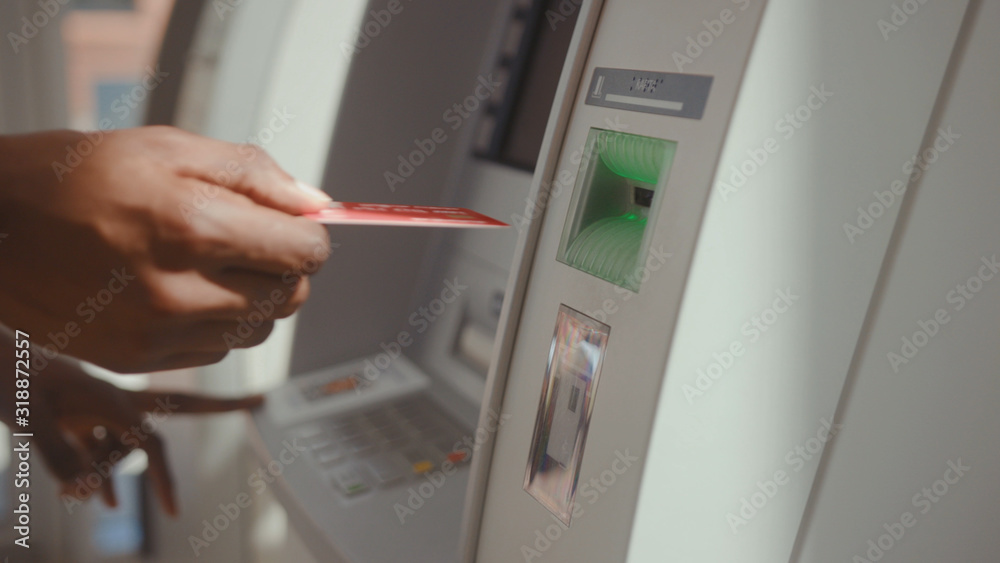 Close-up of man's hand inserting a credti card to withdraw money from bank account. Young african man using an ATM cash machine in a break. Close-up of man's hand inserting a credti card to withdraw money from bank account. Young african man using an ATM cash machine in a break.