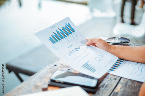 Businessman hold paper graph chart on the table near the river. Working at vocation.