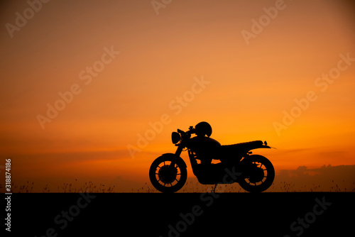 Silhouette of motorcycle parking with sunset background in Thailand  Young Traveller man placed helmet on motorbike. Trip and lifestyle of Motorcycle Concept