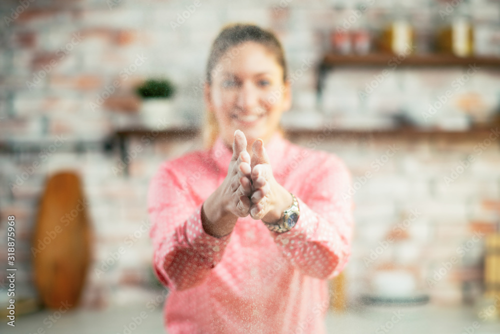 Obraz premium Close up of woman clapping hands and splashing flour. Woman in kitchen.