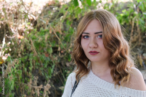 sad young girl at green bushes background