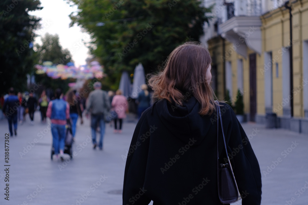 Young woman walking in the street view from behind.