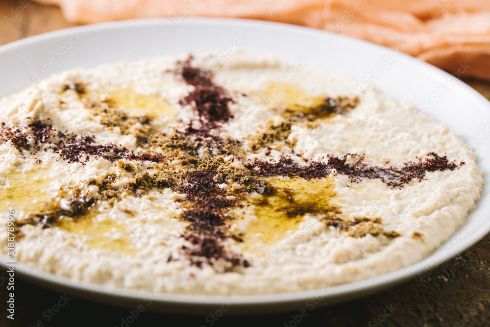 Home made hummus plate , decorated with boiled , herbs, and olive oil on dark background Home made hummus plate , decorated with boiled , herbs, and olive oil on dark background