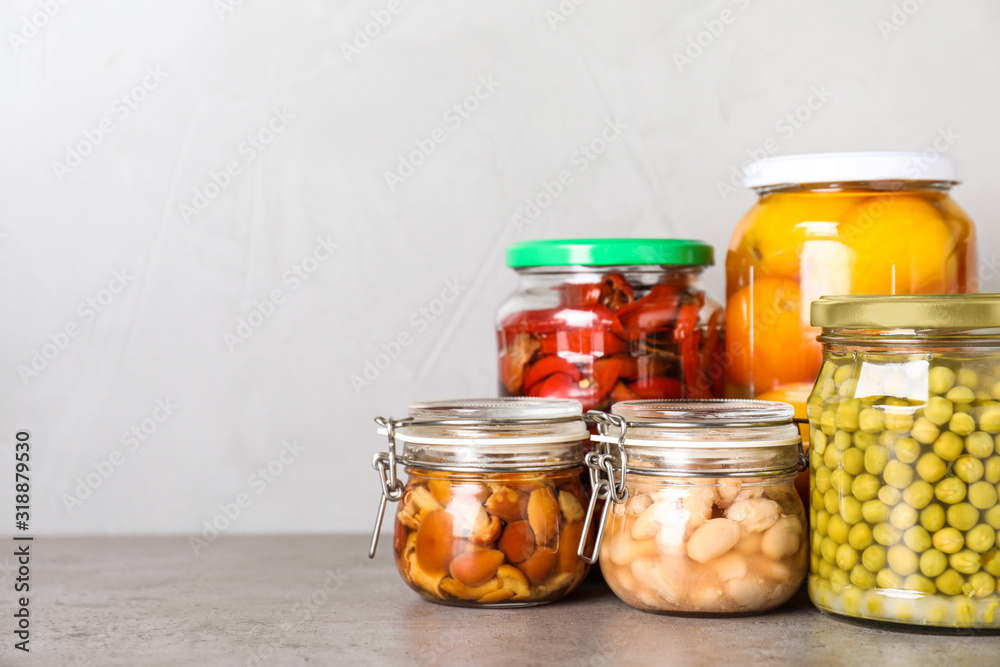 Glass jars with different pickled vegetables on grey table. Space for text Glass jars with different pickled vegetables on grey table. Space for text