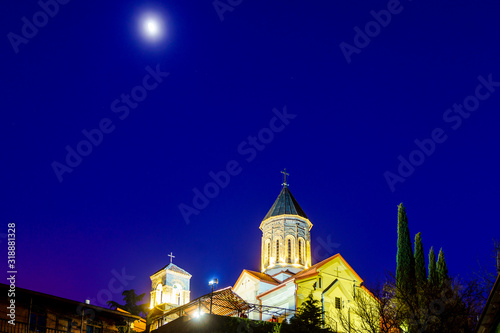 Georgia, Tbilisi all Saints Church at sunset on a winter evening. The dark blue sky. The temple is lit by lanterns photo