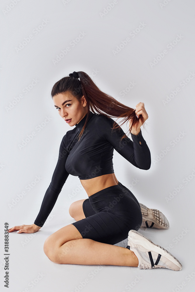 Fototapeta premium Twerk dancing. Sportive woman in black clothes in the studio against white background