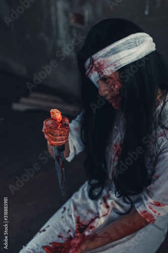 horror scence of women hold knife by hands with blood. Ghost women wear white dress stain blood at abandoned house