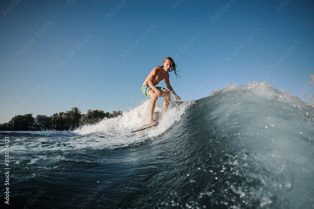 Young wakesurfer conquers a high wave on a board