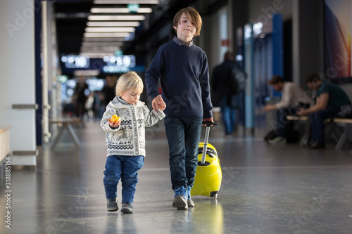 Blonde toddler boy with family, traveling with airplane, running at the airport