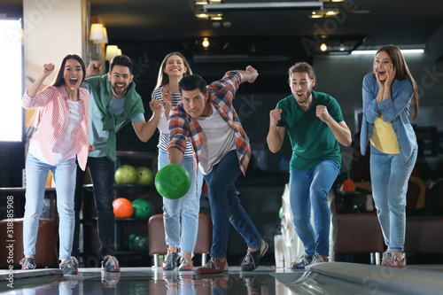 Man throwing ball and spending time with friends in bowling club