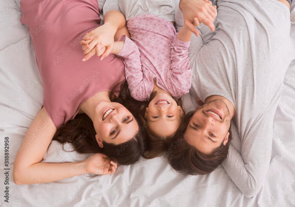Family Portrait Of Cute Little Girl And Her Parents In Bed