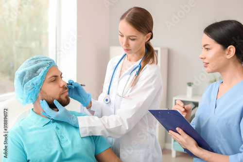 Plastic surgeon examining y...