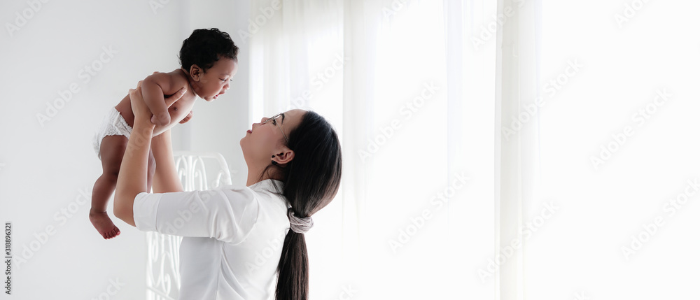 diversity of asian mother holding her mixed race black baby boy african american and asian in white room diversity of asian mother holding her mixed race black baby boy african american and asian in white room