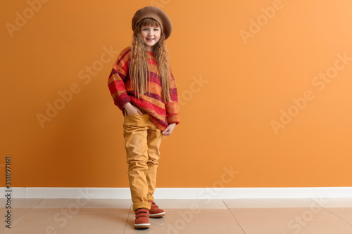 Cute little girl in autumn clothes near color wall