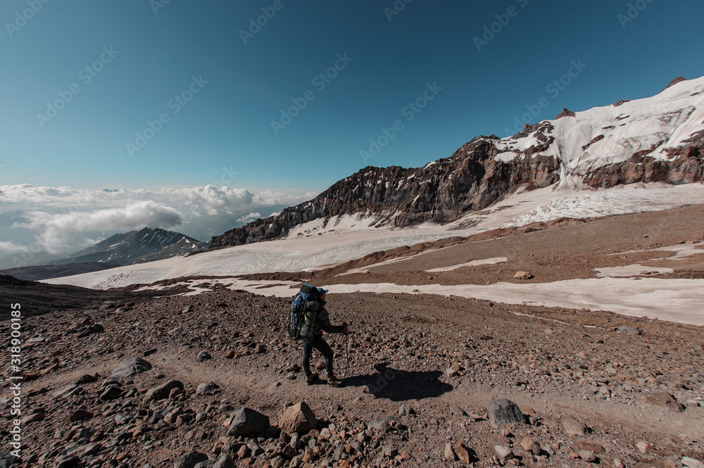 Male hiker stands in front of the mountain sides