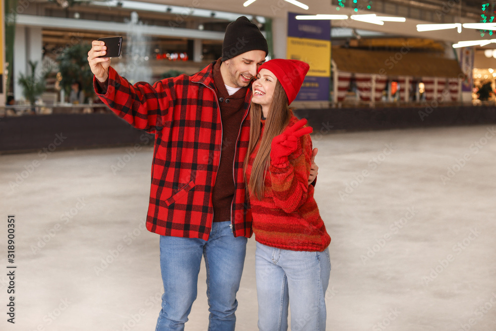 Happy couple taking selfie on skating rink