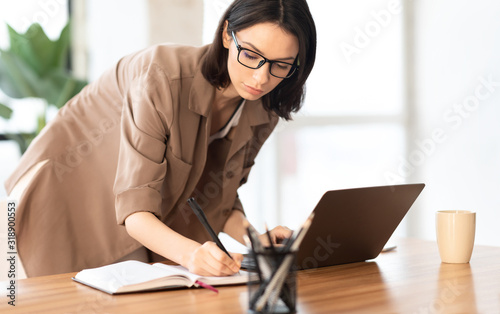Portrait of manager taking notes standing at table