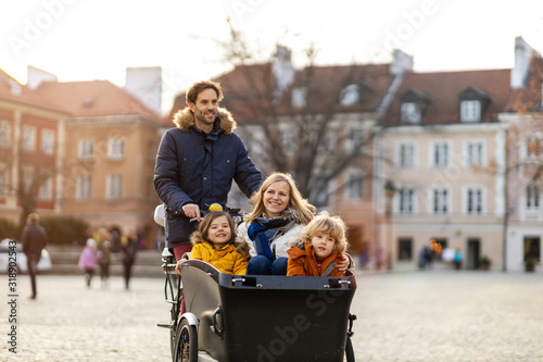 Young family enjoying spending time together, riding in a cargo bicycle photo