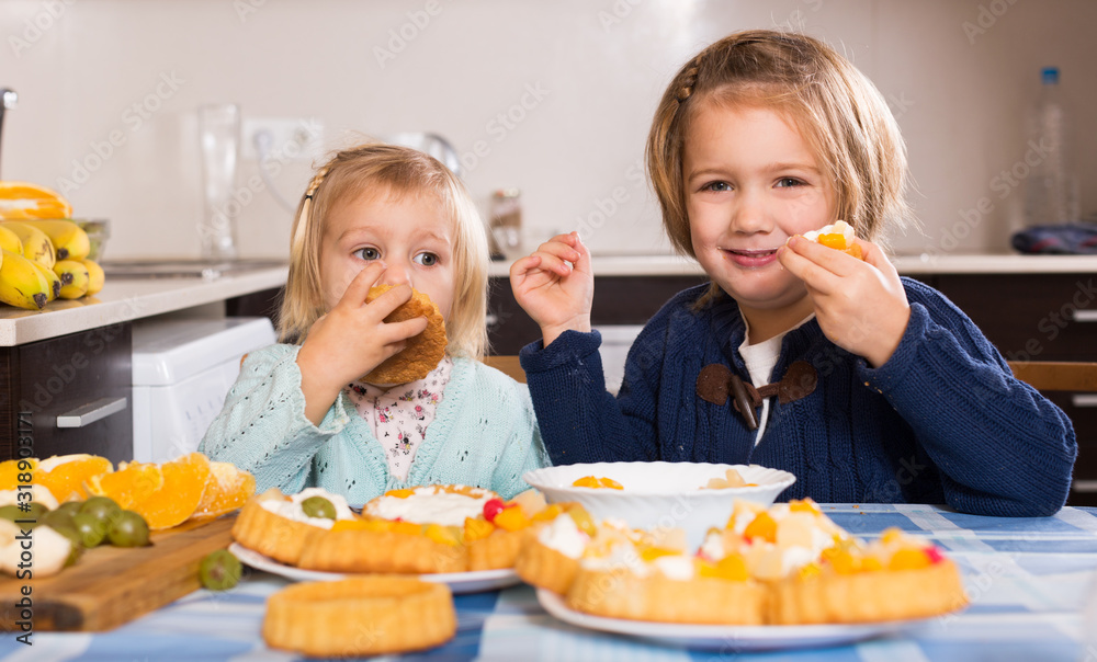 Children eat cakes at kitchen