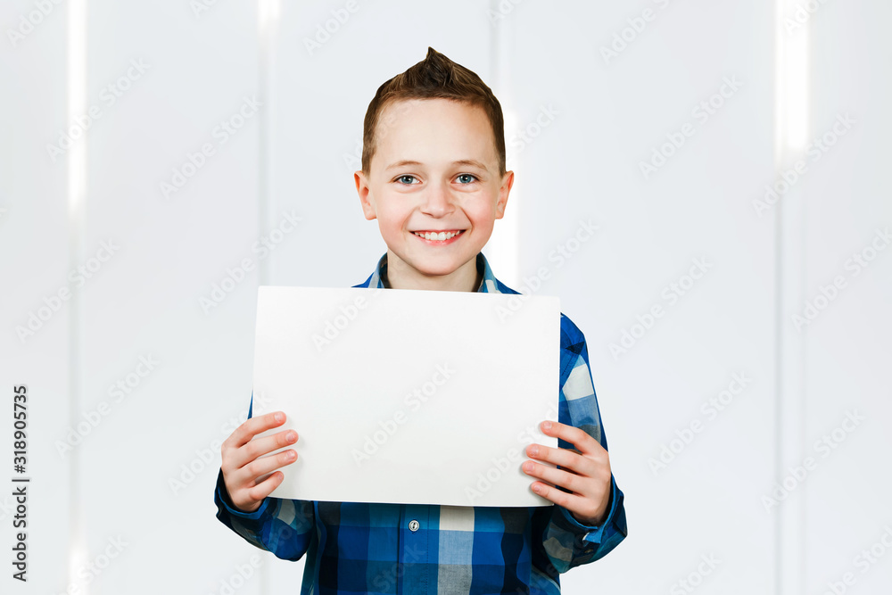 Cute young smiling schooler boy hold blank sign with copy space on white background Cute young smiling schooler boy hold blank sign with copy space on white background