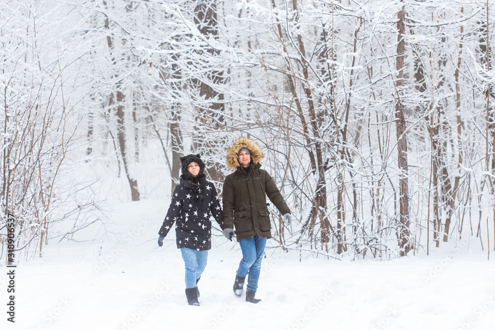 Young couple in love walks in the snowy forest. Active winter holidays.