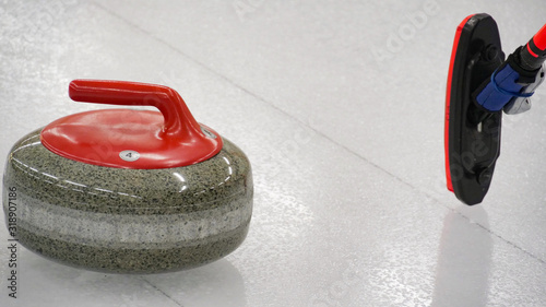 Curling winter, olympic sport. Red curling stone and Ice curling sheet with red and blue circle and visible pebbles 