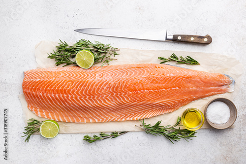 Fresh raw salmon or trout sea fish fillet with spices and herbs on white background, top view photo