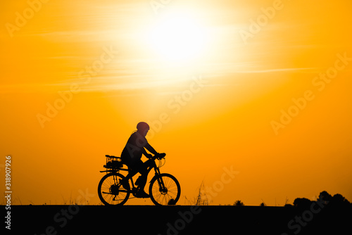 Silhouette woman cycling on sunset background