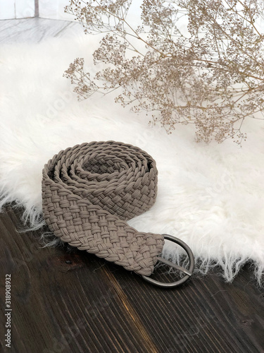 Gray twisted knitted belt on a wooden background