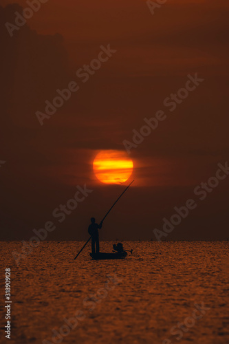 Silhouette fisherman with sunset sky on the lake