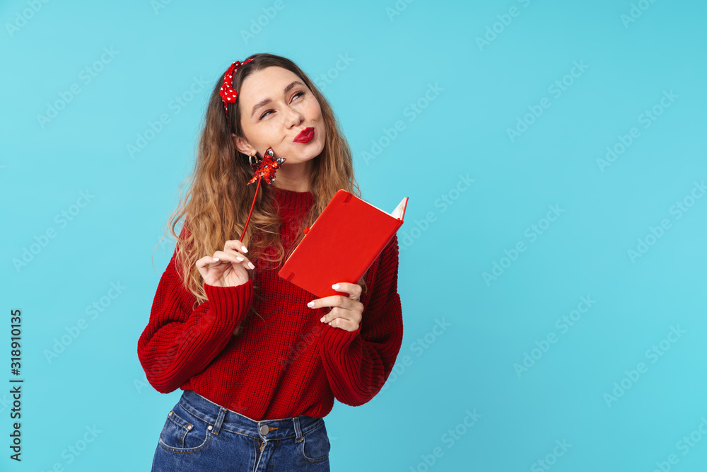 Fototapeta premium Image of dreaming blonde woman holding notebook and magic wand