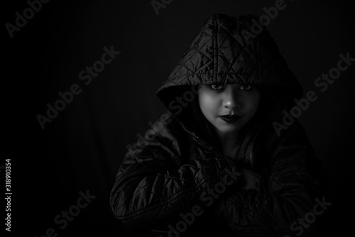 Monochrome fashion portrait of an young Indian Bengali brunette woman with maroon winter hoodie jacket in black copy space background. Indian lifestyle and fashion photography.