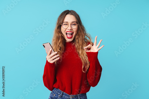 Εκτύπωση καμβά Image of joyful woman holding cellphone and gesturing ok sign