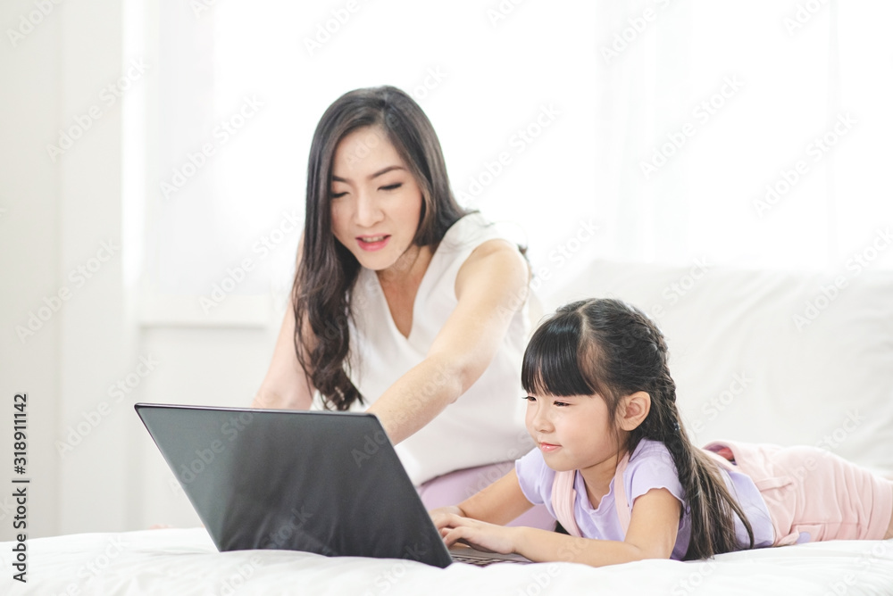 Mother watching her daughter who is learning to use the computer. Mother watching her daughter who is learning to use the computer.