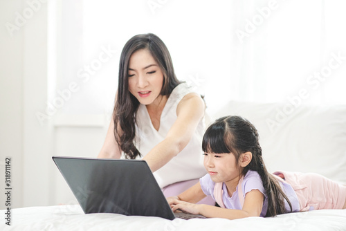 Mother watching her daughter who is learning to use the computer.