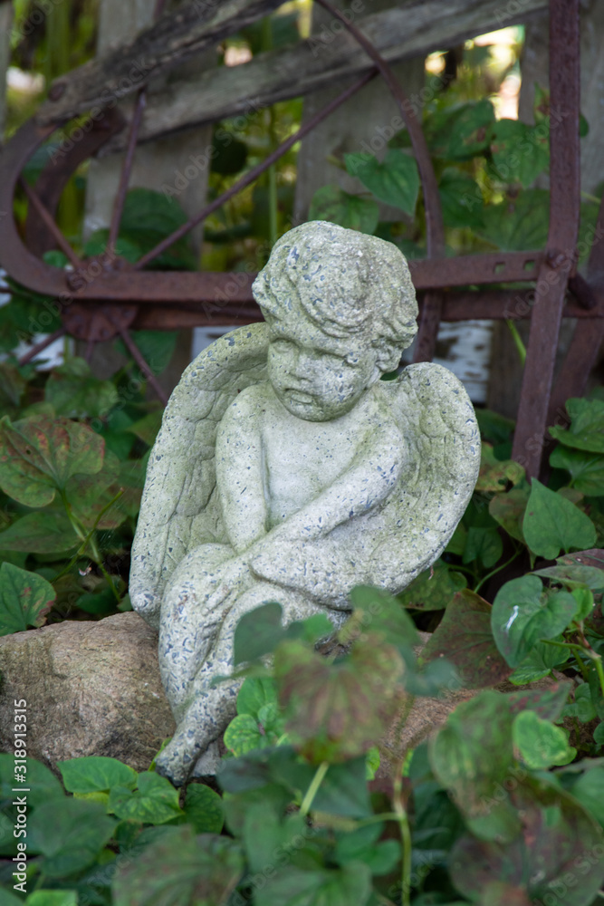 Close up of stone cupid angel garden statue