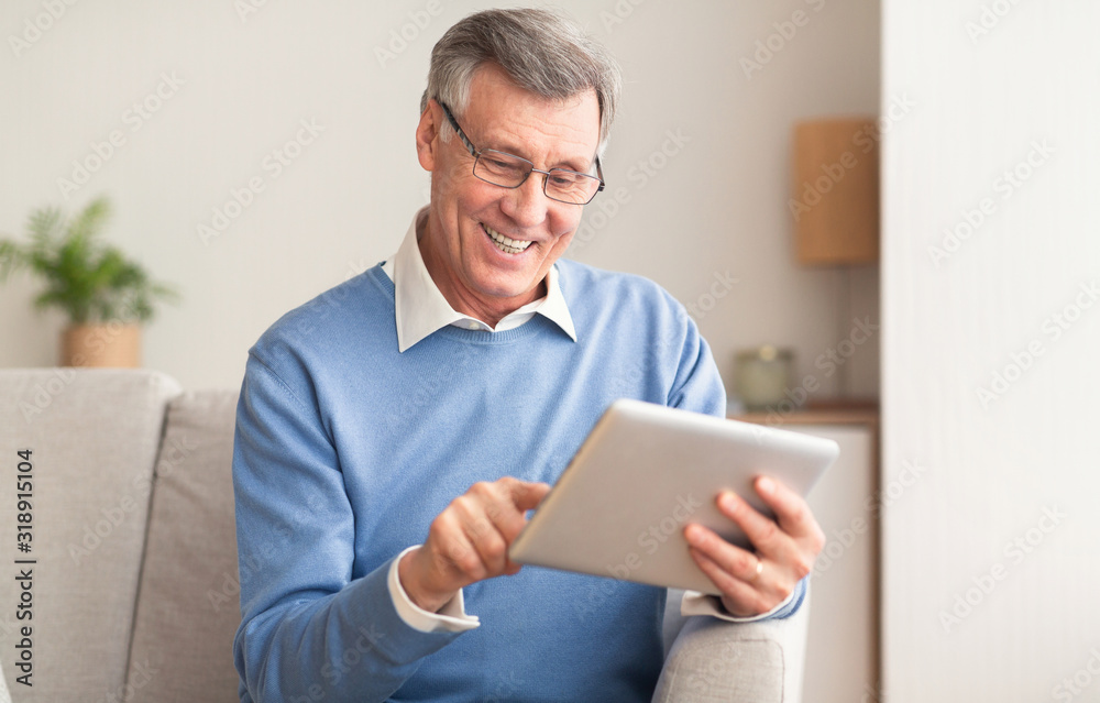 Joyful Retired Man Using Digital Tablet Sitting On Couch Indoor Joyful Retired Man Using Digital Tablet Sitting On Couch Indoor