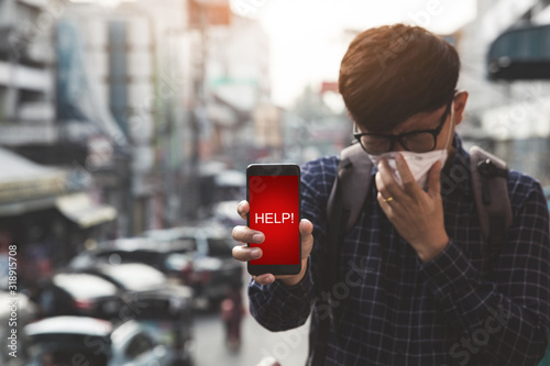 Unfocused man holding smartphone in hand and there is a warning message help.Concept of coronavirus quarantine. MERS-Cov, Novel coronavirus (2019-nCoV),Air pollution photo