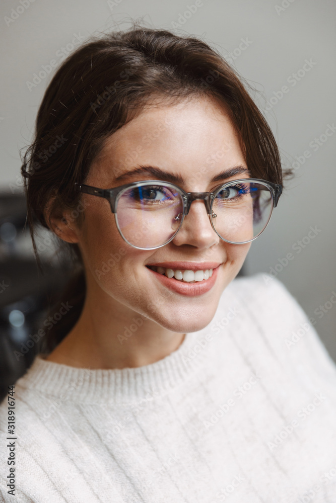 Image of young woman wearing eyeglasses smiling at camera indoors Image of young woman wearing eyeglasses smiling at camera indoors