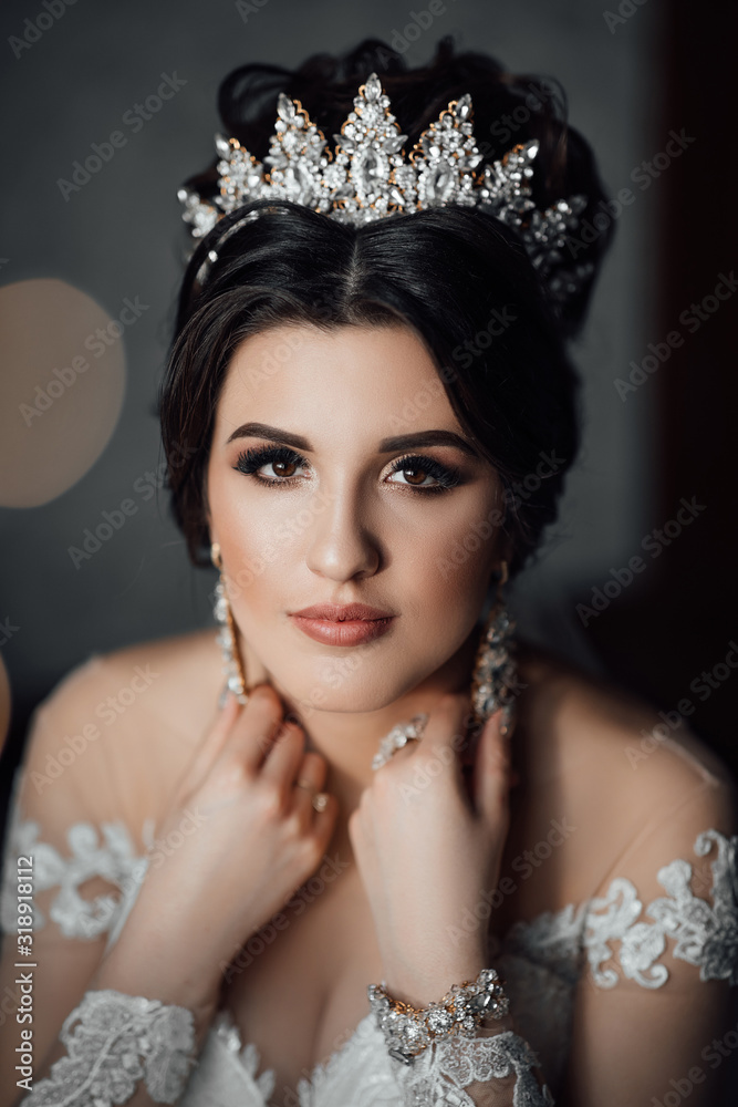 Gorgeous female bride touches the earrings. Beautiful bride with makeup and hair style. Sexy bride posing. Wedding morning of the bride. Gorgeous female bride touches the earrings. Beautiful bride with makeup and hair style. Sexy bride posing. Wedding morning of the bride.