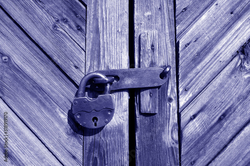 Grungy wooden door with lock in blue tone.