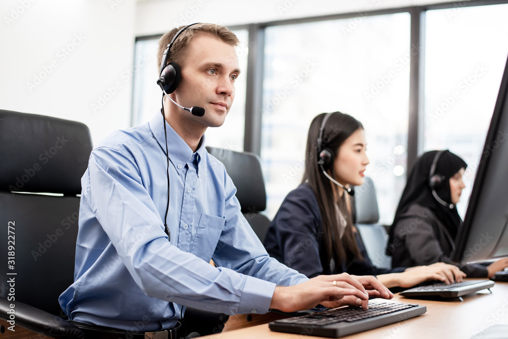Male call center employees are working. His seriousness and willingness to work. His friedns working in the background