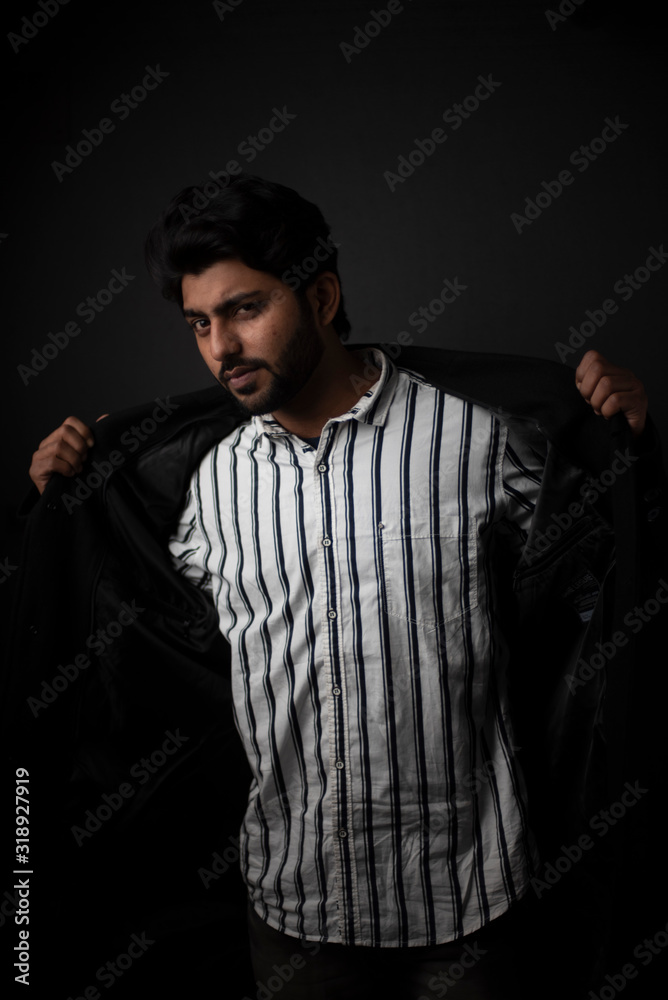 Fashion portrait of young and handsome Indian Bengali brunette man with striped formal shirt, black suit in black copy space background. Indian lifestyle and fashion photograph Fashion portrait of young and handsome Indian Bengali brunette man with striped formal shirt, black suit in black copy space background. Indian lifestyle and fashion photograph
