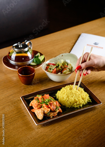 woman eating rice and vegetables with sticks at an Asian restaurant