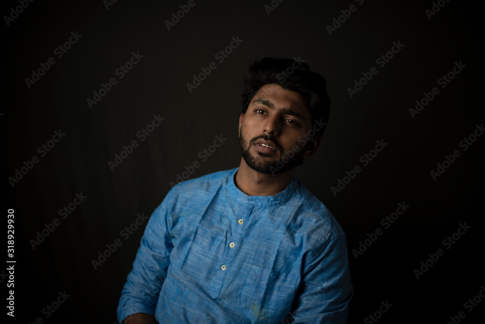 Fashion portrait of young and handsome Indian Bengali brunette man with traditional cotton wear in black copy space background. Indian lifestyle and fashion photography.