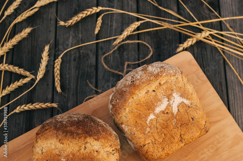 Fresh homemade bread with sunflower seeds, isolated on a wooden background. Side view, top view, close-up view. Ears of wheat, rye. photo