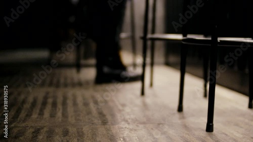Young woman legs wearing black leather boots walking in the restaurant near bar chairs. Leather woman boots in the restaurant interiror. photo