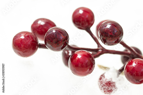 Little decorative shiny fake berries balls red spots with white fur background