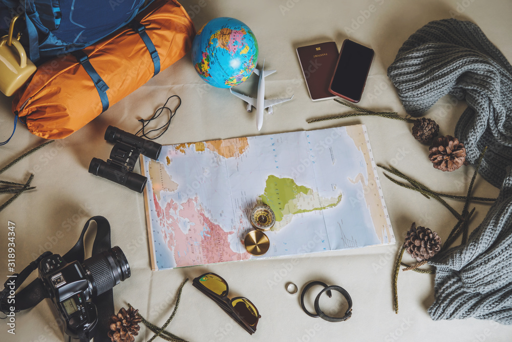 Obraz premium Tourist planning vacation with the help of world map with other travel accessories around. smartphone, film camera and sunglasses on a White background. Travel backpack